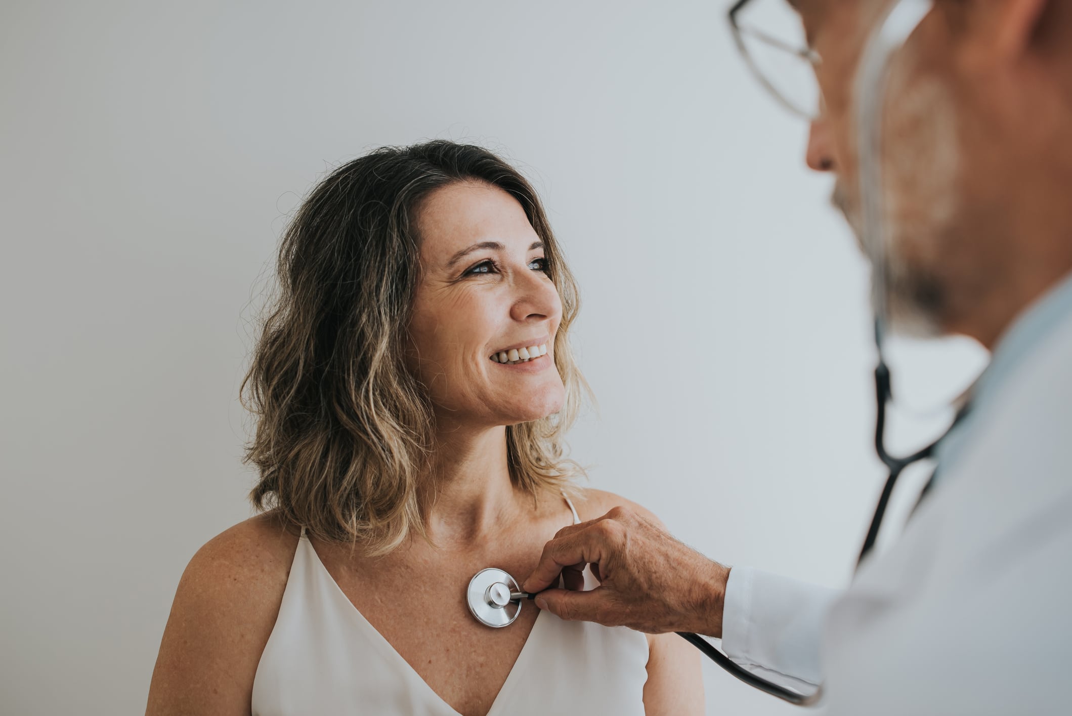 doctor listening to happy woman's chest